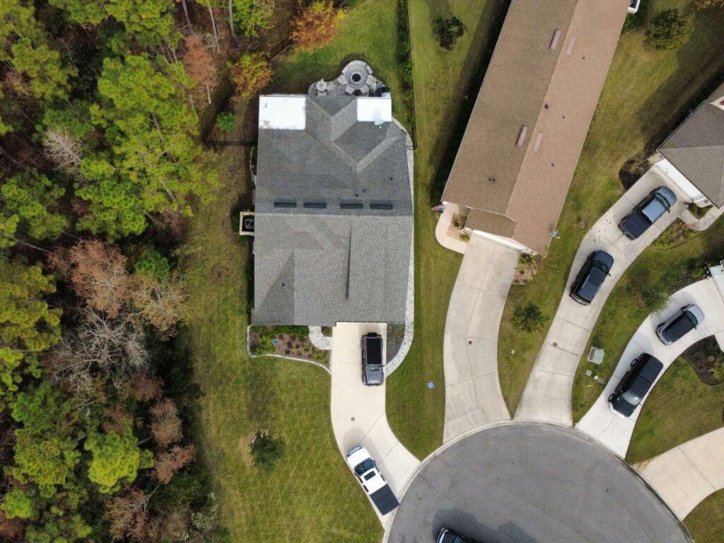 Aerial view of a well-maintained home and lawn beside a wooded area in St. Johns County