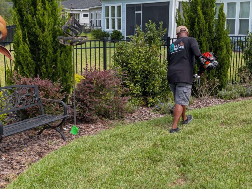 G&G Home Lawns team member performing hedge trimming and landscape bed maintenance at residential home in St. Augustine